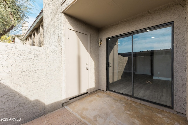 property entrance featuring stucco siding, a patio area, and fence