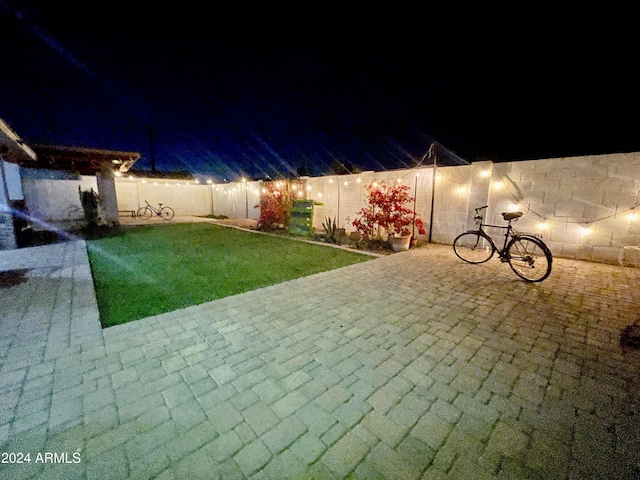 patio at night featuring a yard