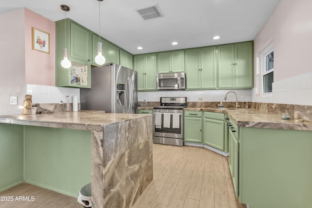 kitchen with decorative light fixtures, kitchen peninsula, stainless steel appliances, and green cabinetry