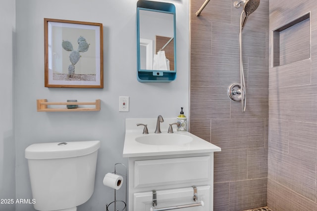 bathroom featuring vanity, toilet, and a tile shower