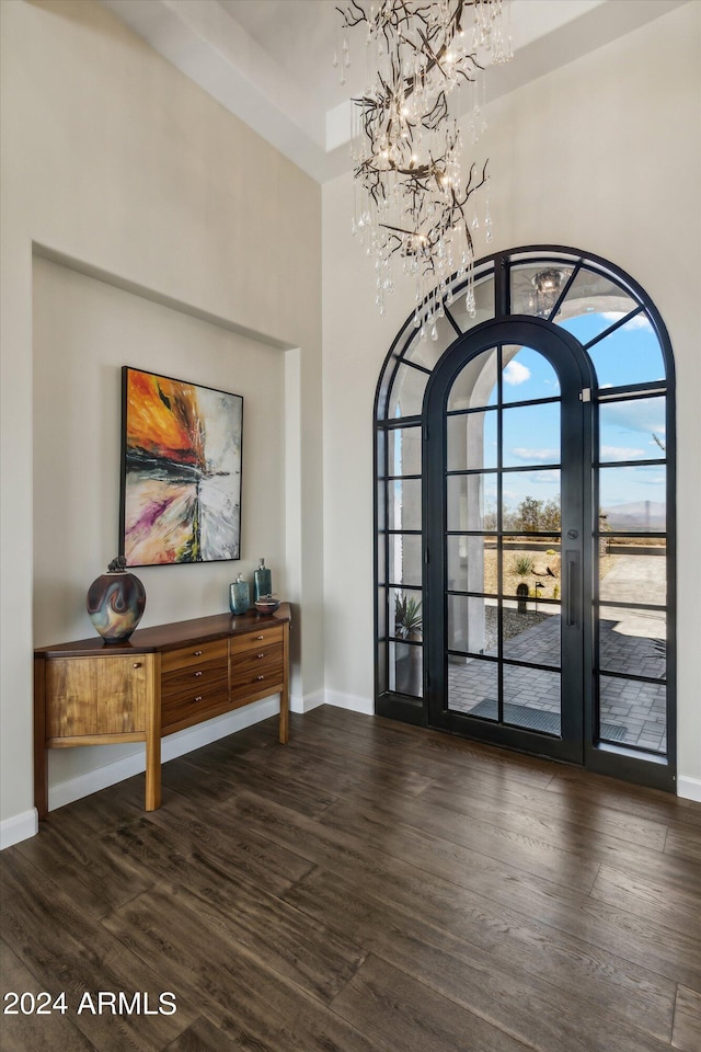 foyer featuring a towering ceiling, dark hardwood / wood-style floors, a chandelier, and french doors