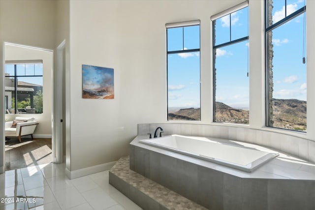 bathroom with tile patterned floors, tiled bath, and a mountain view