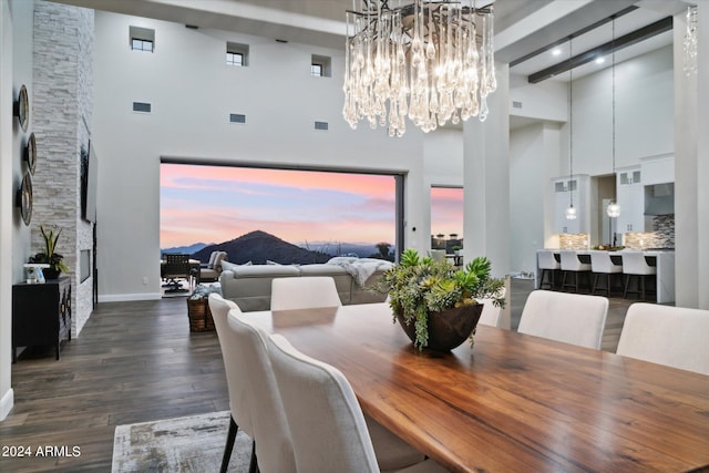 dining room featuring dark hardwood / wood-style flooring, a high ceiling, and an inviting chandelier