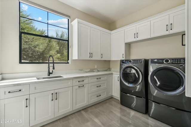 clothes washing area with cabinets, sink, and washing machine and dryer