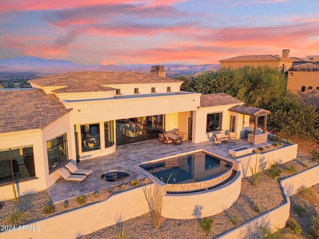 pool at dusk featuring a mountain view, a fire pit, and a patio area