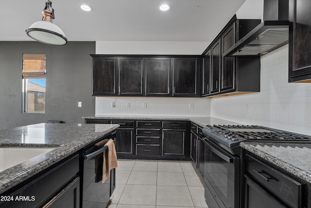 kitchen featuring black appliances, wall chimney exhaust hood, dark stone countertops, light tile patterned floors, and decorative light fixtures