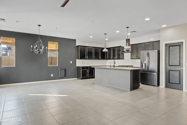 kitchen with a kitchen island with sink, wall chimney exhaust hood, appliances with stainless steel finishes, decorative light fixtures, and a chandelier