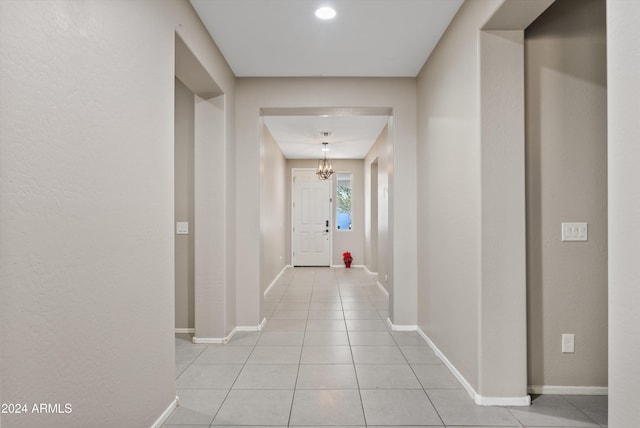 corridor with light tile patterned floors and a chandelier