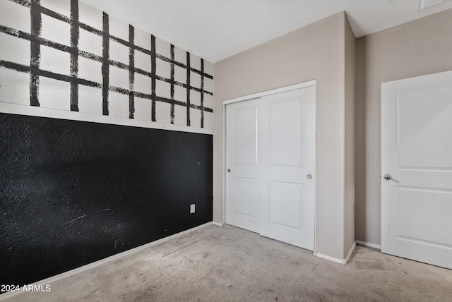 unfurnished bedroom with light colored carpet and a closet