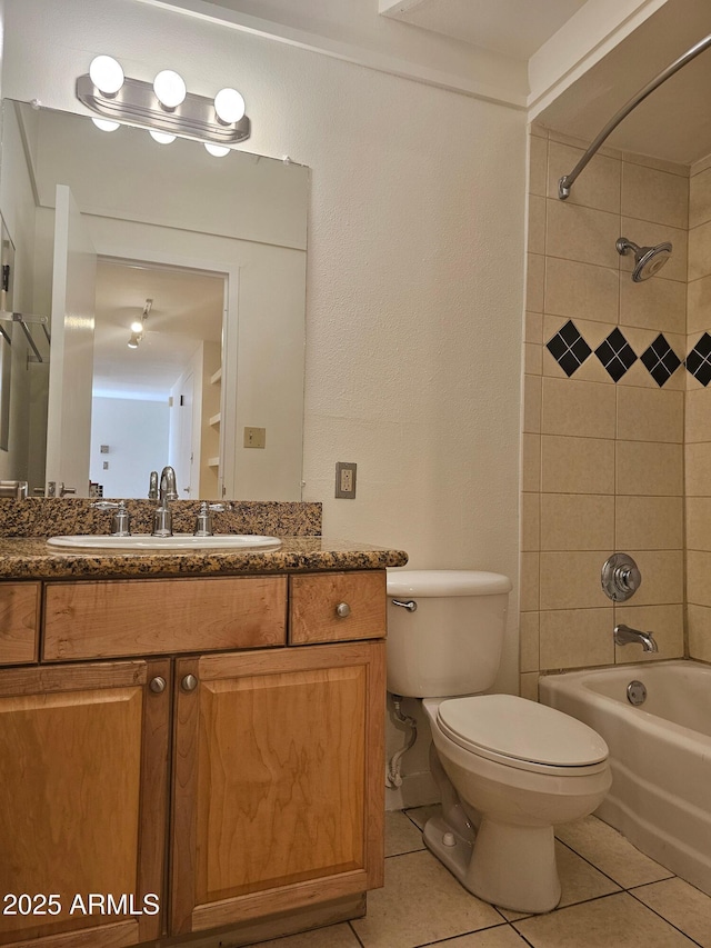 full bathroom with tile patterned flooring, vanity, tiled shower / bath combo, and toilet