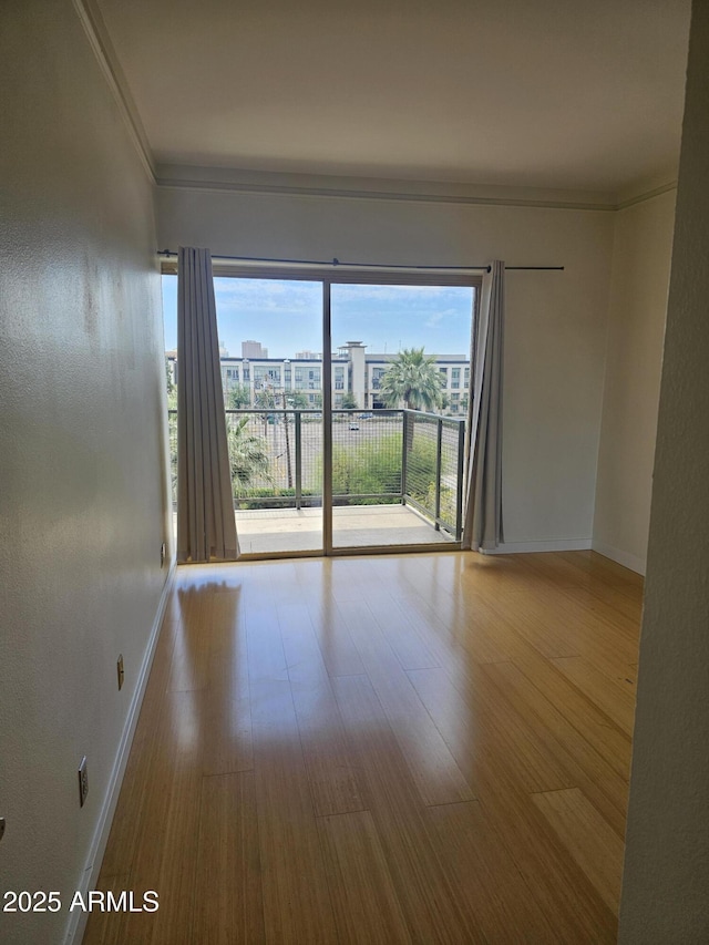 spare room featuring baseboards, ornamental molding, and wood finished floors