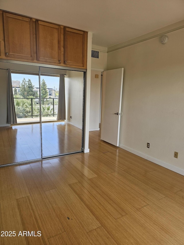 unfurnished bedroom featuring light wood finished floors, baseboards, and visible vents