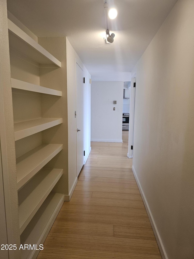 hallway featuring light wood-style flooring and baseboards