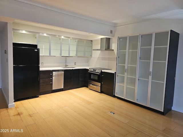 kitchen with light wood-style floors, wall chimney exhaust hood, appliances with stainless steel finishes, and a sink