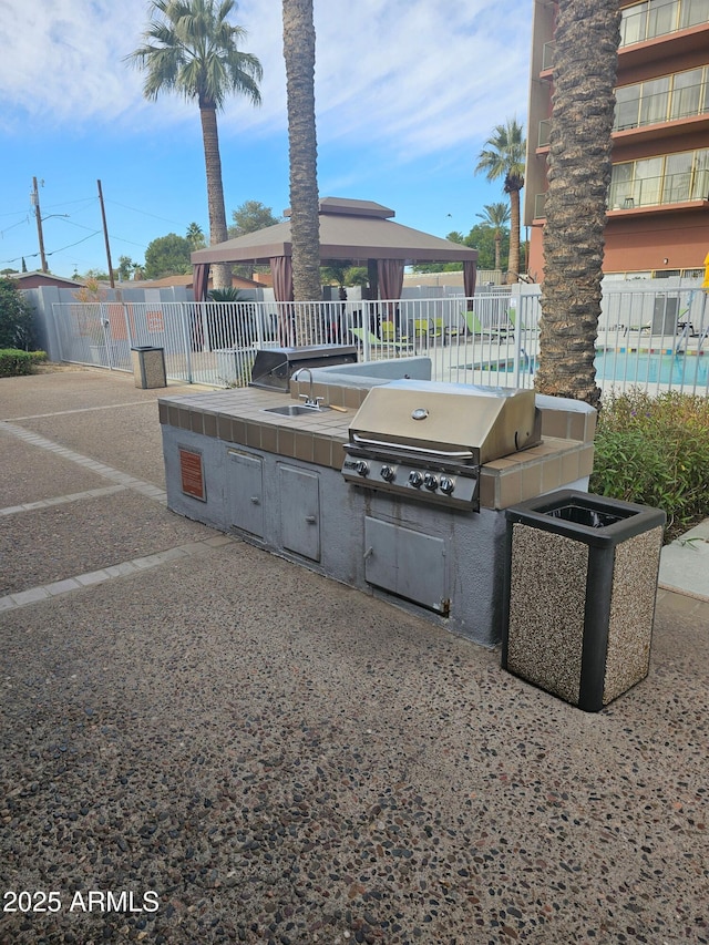 view of patio featuring a gazebo, grilling area, exterior kitchen, and sink