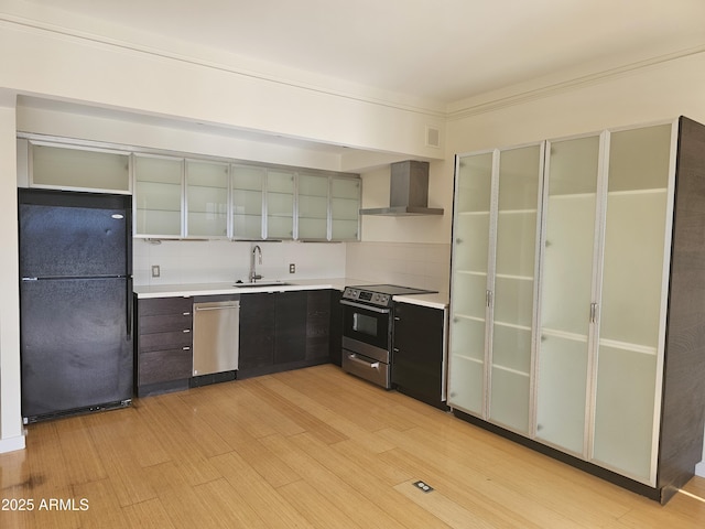 kitchen with sink, stainless steel appliances, tasteful backsplash, light hardwood / wood-style floors, and wall chimney exhaust hood