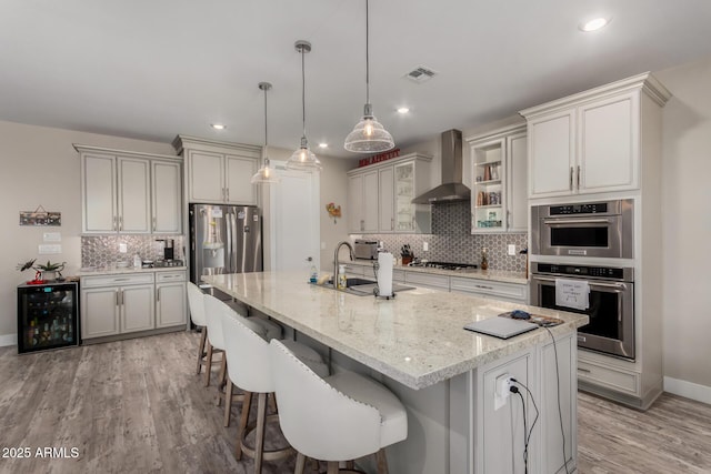 8741 N 185th Ave, Waddell, AZ 85355 - kitchen featuring wall chimney exhaust hood, beverage cooler, decorative backsplash, light wood-type flooring, and a breakfast bar