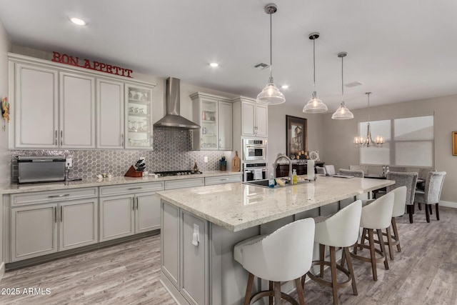 8741 N 185th Ave, Waddell, AZ 85355 - kitchen featuring wall chimney exhaust hood, appliances with stainless steel finishes, a kitchen breakfast bar, light wood finished floors, and recessed lighting