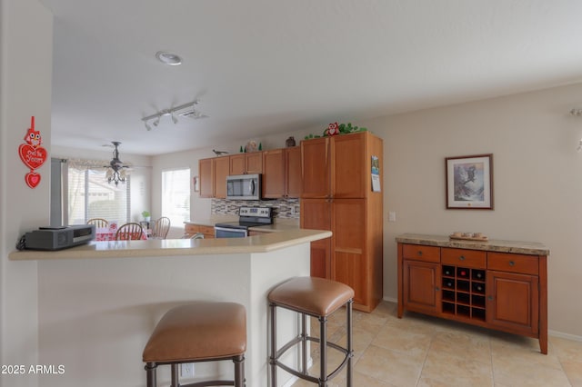 kitchen featuring backsplash, a kitchen breakfast bar, kitchen peninsula, and appliances with stainless steel finishes