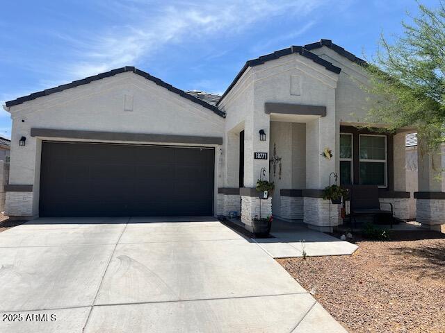 18711 W Farmer Rd, Buckeye, AZ 85326 - view of front of house with driveway, a garage, stucco siding, and stone siding