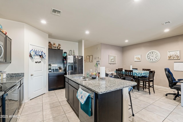 18711 W Farmer Rd, Buckeye, AZ 85326 - kitchen with a sink, appliances with stainless steel finishes, a breakfast bar, light tile patterned floors, and recessed lighting