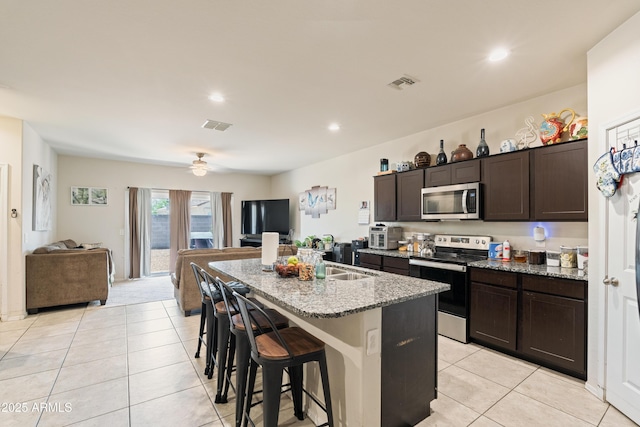 18711 W Farmer Rd, Buckeye, AZ 85326 - kitchen featuring stainless steel appliances, light tile patterned flooring, a kitchen bar, an island with sink, and recessed lighting