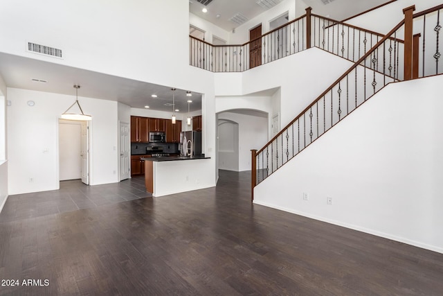 unfurnished living room with a towering ceiling and dark wood-type flooring