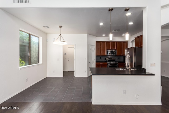 kitchen with kitchen peninsula, appliances with stainless steel finishes, backsplash, sink, and hanging light fixtures