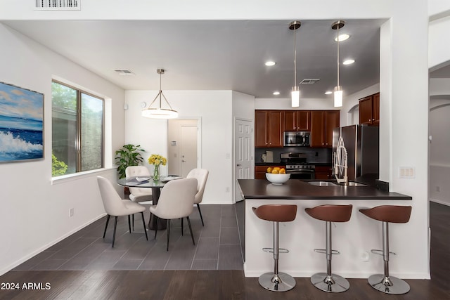 kitchen featuring pendant lighting, a kitchen breakfast bar, sink, appliances with stainless steel finishes, and kitchen peninsula