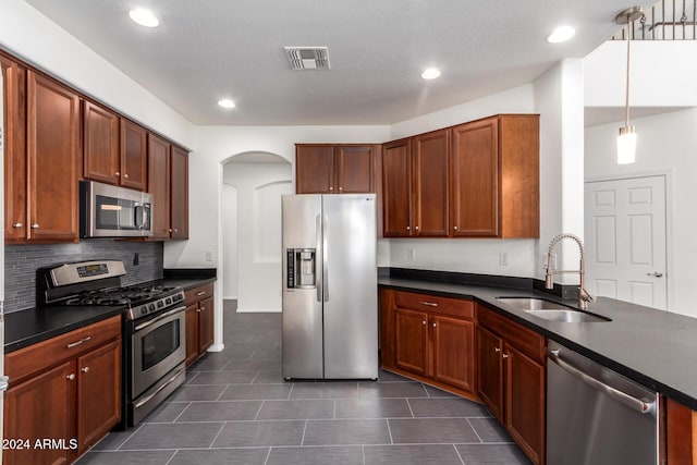 kitchen with backsplash, hanging light fixtures, sink, and appliances with stainless steel finishes