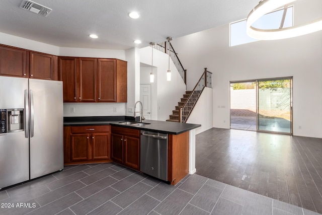 kitchen with kitchen peninsula, sink, pendant lighting, and appliances with stainless steel finishes