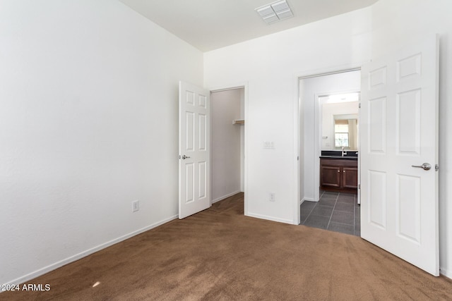 unfurnished bedroom featuring connected bathroom and dark carpet