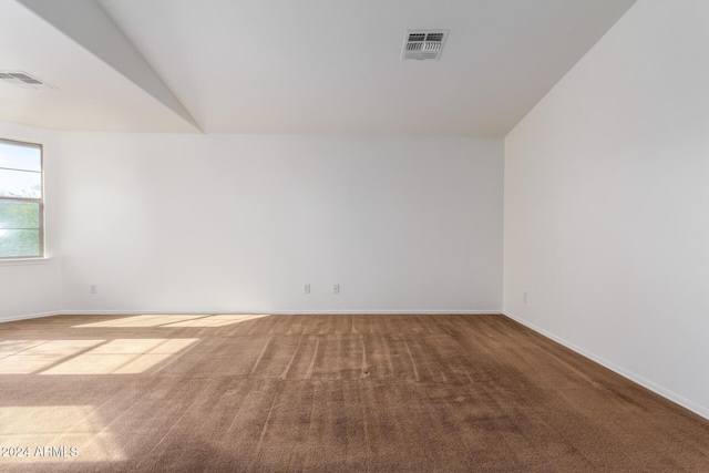 carpeted empty room with lofted ceiling