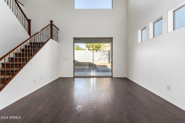 unfurnished living room featuring dark hardwood / wood-style flooring and a towering ceiling