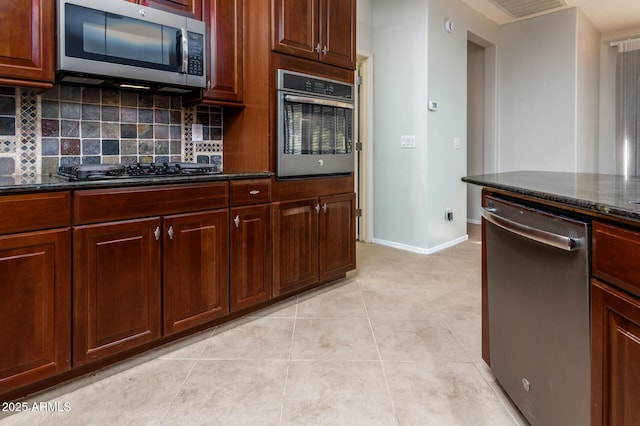 kitchen with light tile patterned floors, stainless steel appliances, tasteful backsplash, and dark stone countertops