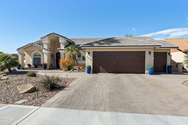 view of front of property with an attached garage, decorative driveway, and stucco siding