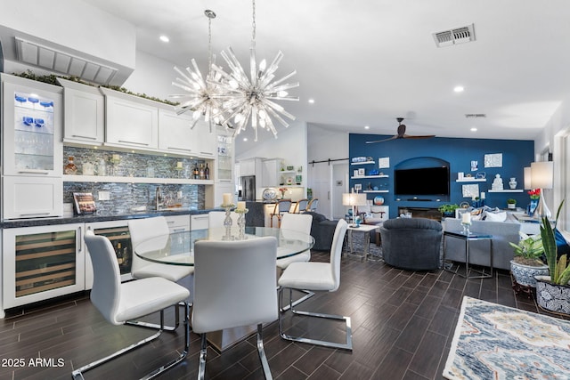 dining room with wine cooler, visible vents, a barn door, wood tiled floor, and ceiling fan with notable chandelier