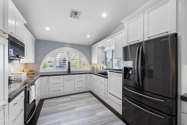 kitchen featuring dark countertops, visible vents, decorative backsplash, white cabinetry, and black appliances