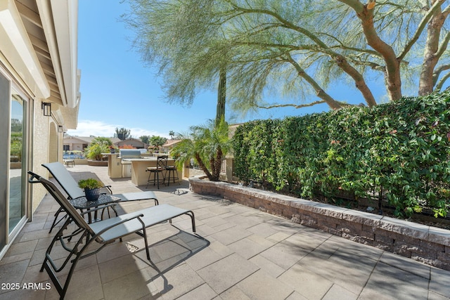 view of patio / terrace featuring fence, an outdoor kitchen, and outdoor wet bar