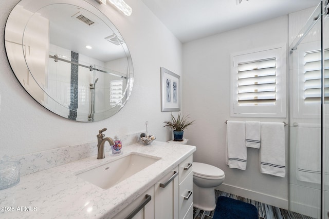 full bathroom featuring toilet, vanity, visible vents, baseboards, and a shower stall