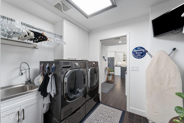 laundry area featuring dark wood-style floors, visible vents, cabinet space, a sink, and separate washer and dryer