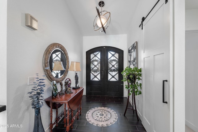 foyer featuring wood finish floors, french doors, a barn door, vaulted ceiling, and baseboards