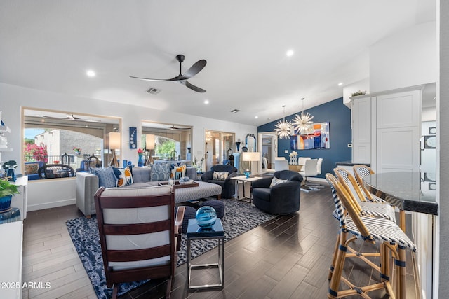 living room featuring lofted ceiling, ceiling fan with notable chandelier, wood finished floors, and a wealth of natural light