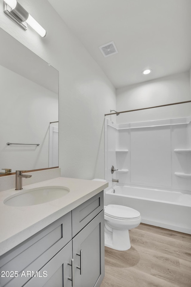 full bathroom featuring shower / washtub combination, visible vents, toilet, vanity, and wood finished floors