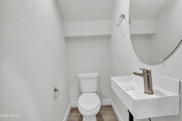 bathroom featuring toilet, a sink, baseboards, and wood finished floors