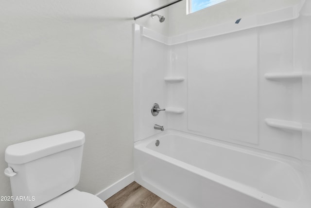 bathroom with shower / washtub combination, wood finished floors, toilet, and baseboards