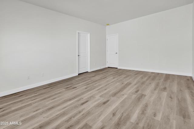 spare room with baseboards and wood finished floors