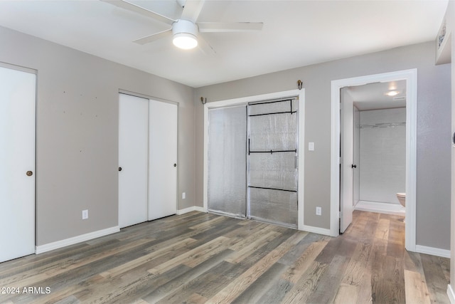 unfurnished bedroom with dark hardwood / wood-style floors, ensuite bath, ceiling fan, and multiple closets