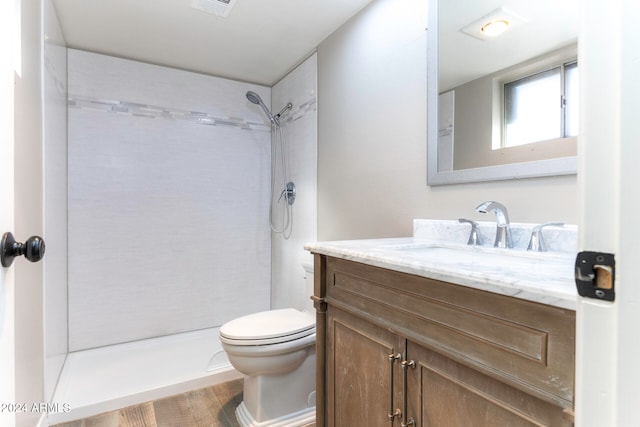 bathroom featuring tiled shower, vanity, hardwood / wood-style flooring, and toilet