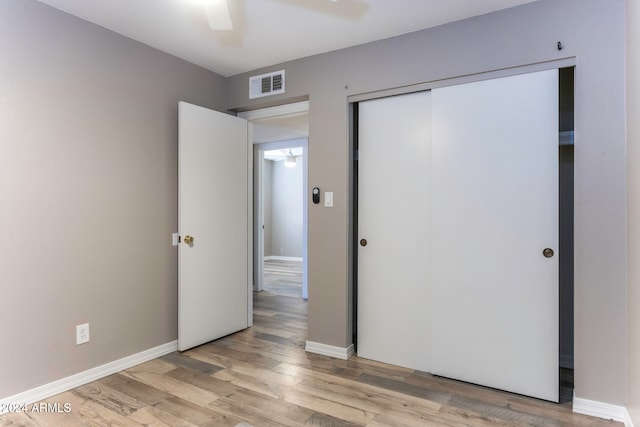 unfurnished bedroom featuring ceiling fan, a closet, and light wood-type flooring